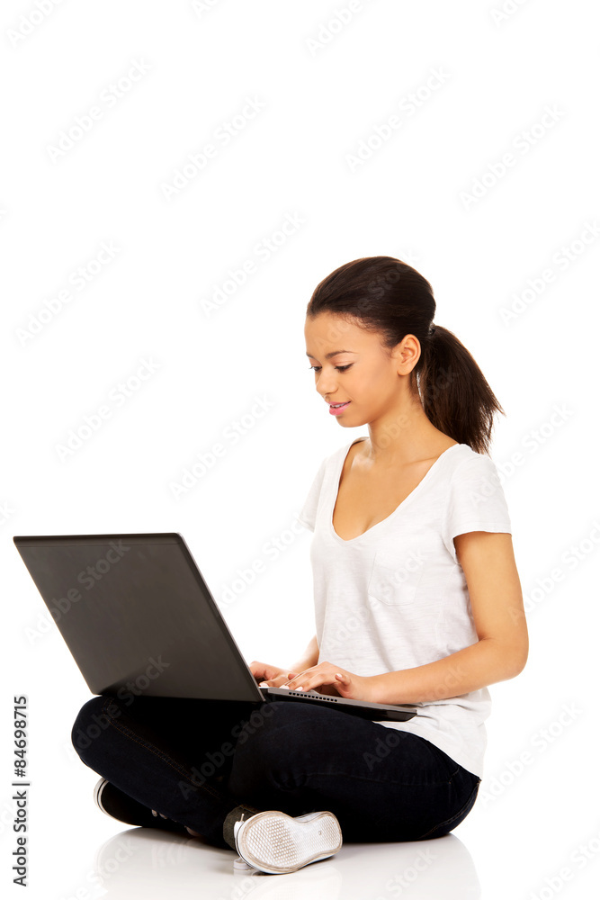 Teen sitting cross legged with laptop. Teen sitting cross legged with laptop.