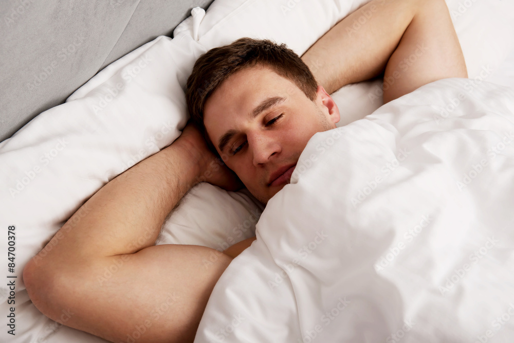 Handsome young man lying in bed.