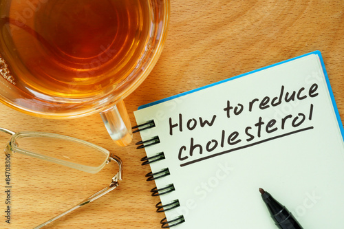 Fotografie Paper with  How to reduce cholesterol on a wooden board.