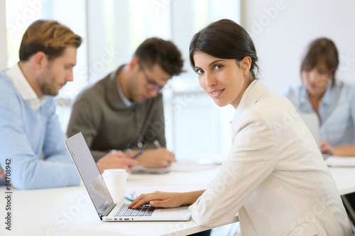 Businesswoman working on laptop, shared workspace