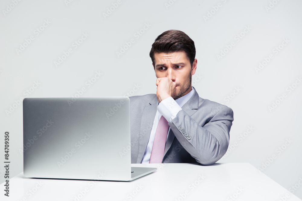 Thoughtful businessman sitting at the table with laptop Thoughtful businessman sitting at the table with laptop