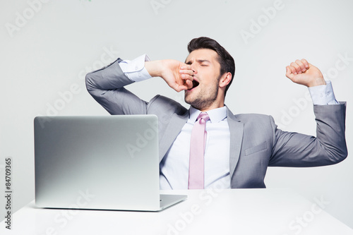 Businessman sitting at the table and yawning