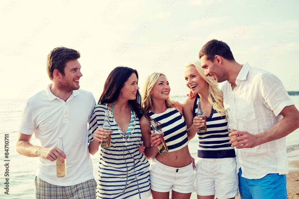 smiling friends with drinks in bottles on beach smiling friends with drinks in bottles on beach