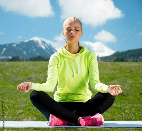 woman sitting in lotus pose doing yoga outdoors