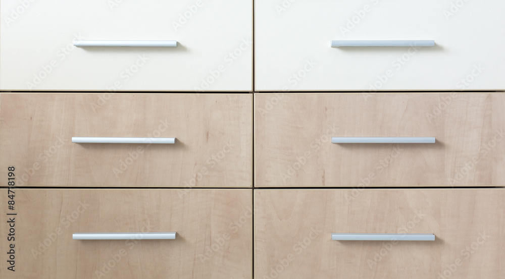 Cropped cabinet with six symmetric drawers. Abstract image of side furniture cabinet business desk wooden box two light and four dark with modern looking grey metallic handles Cropped cabinet with six symmetric drawers. Abstract image of side furniture cabinet business desk wooden box two light and four dark with modern looking grey metallic handles