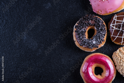 hand decorated donuts on black slate ,food border background,
