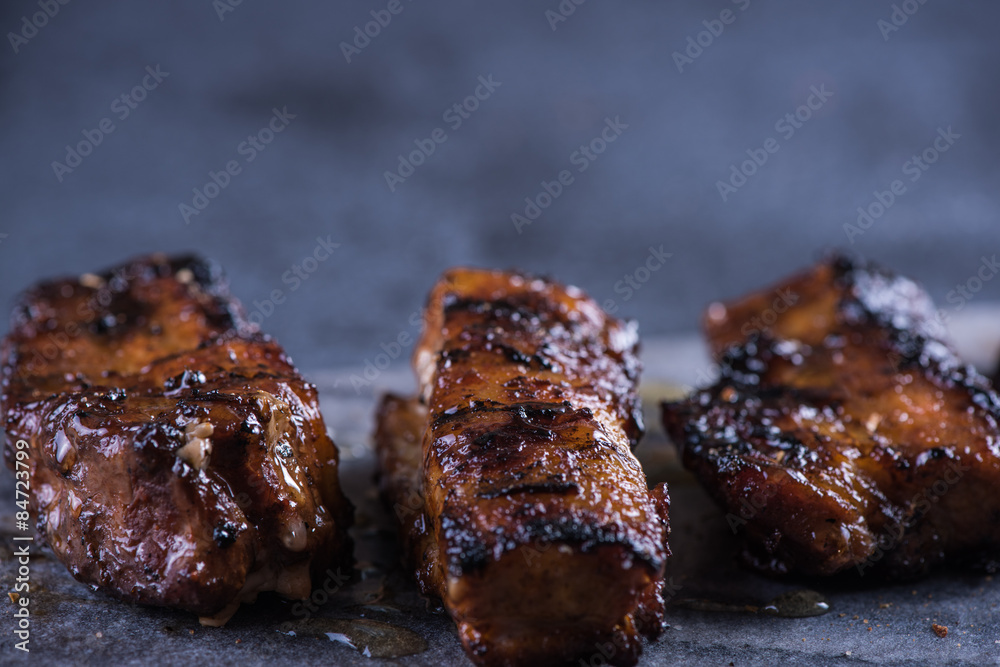 Grilled pork belly slices on marble board and slate background Grilled pork belly slices on marble board and slate background