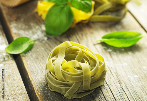  Italian pasta with fresh basil on the wooden surface. Selective focus