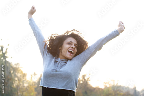 Carefree young woman smiling with arms raised