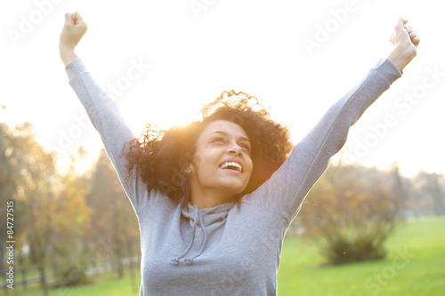 Cheerful young woman smiling with arms raised