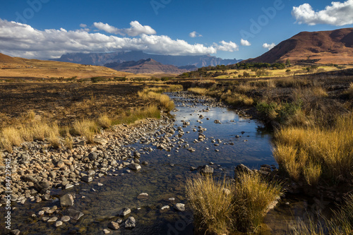 Rocky shallow riverbed surrounded by dry  burnt grassy landscape