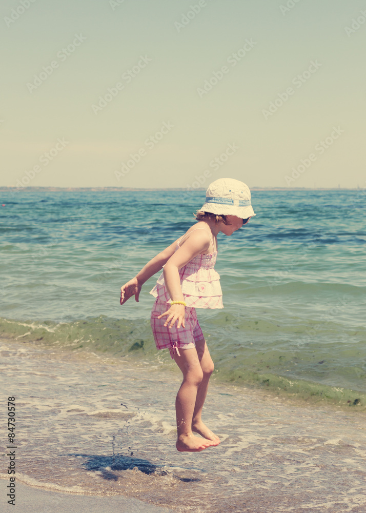Little girl running and playing on the beach. The image is tinte Little girl running and playing on the beach. The image is tinte