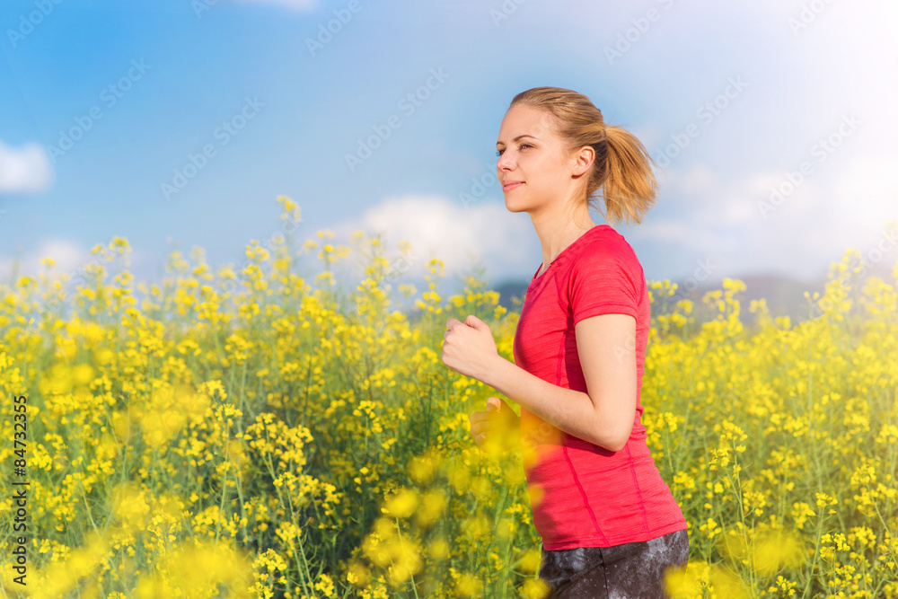 Fototapeta premium Beautiful young girl running in a canola field