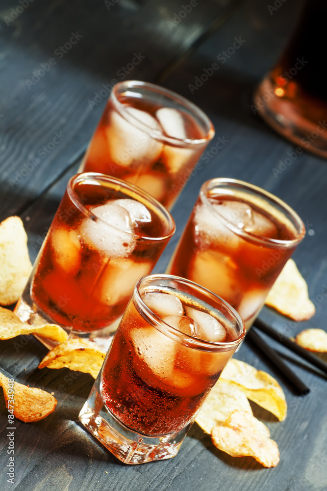 Cola with ice in glasses and chips, selective focus Cola with ice in glasses and chips, selective focus