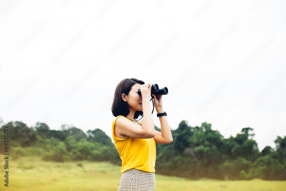 Women and binoculars in hands on green meadow with focus on a binocular