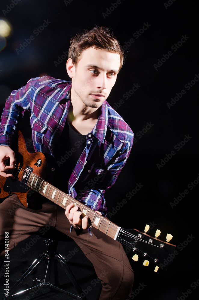 Obraz premium Man playing guitar in dark room