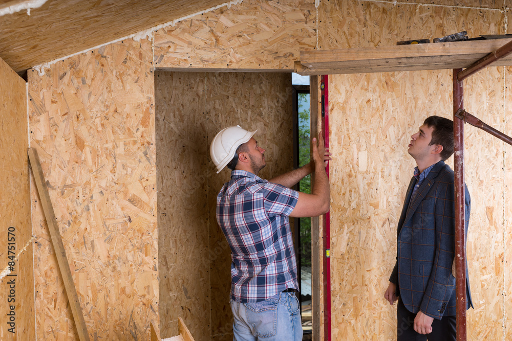 Architect and Worker Checking Levels on Door Frame Architect and Worker Checking Levels on Door Frame