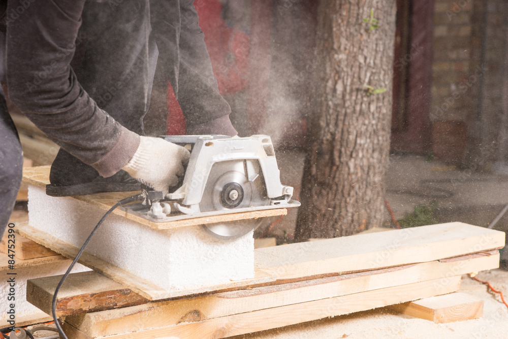 Man Using Power Saw to Cut Planks of Wood