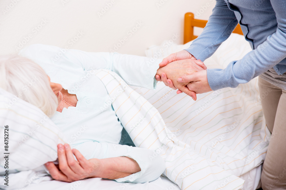 Seniorin liegt im Bett Hilfe von Krankenschwester Seniorin liegt im Bett Hilfe von Krankenschwester