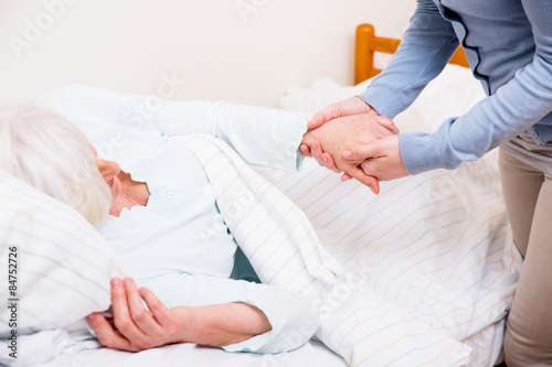 Seniorin liegt im Bett Hilfe von Krankenschwester 