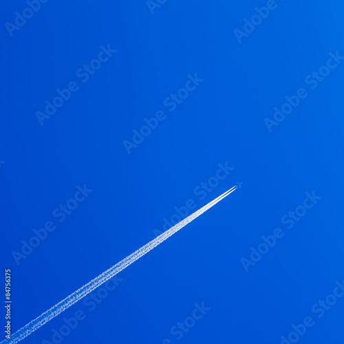 White contrail trace of plane on clear blue sky.