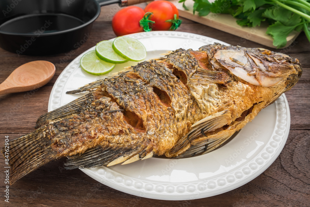 Fried fish on plate with vegetables and pan Fried fish on plate with vegetables and pan