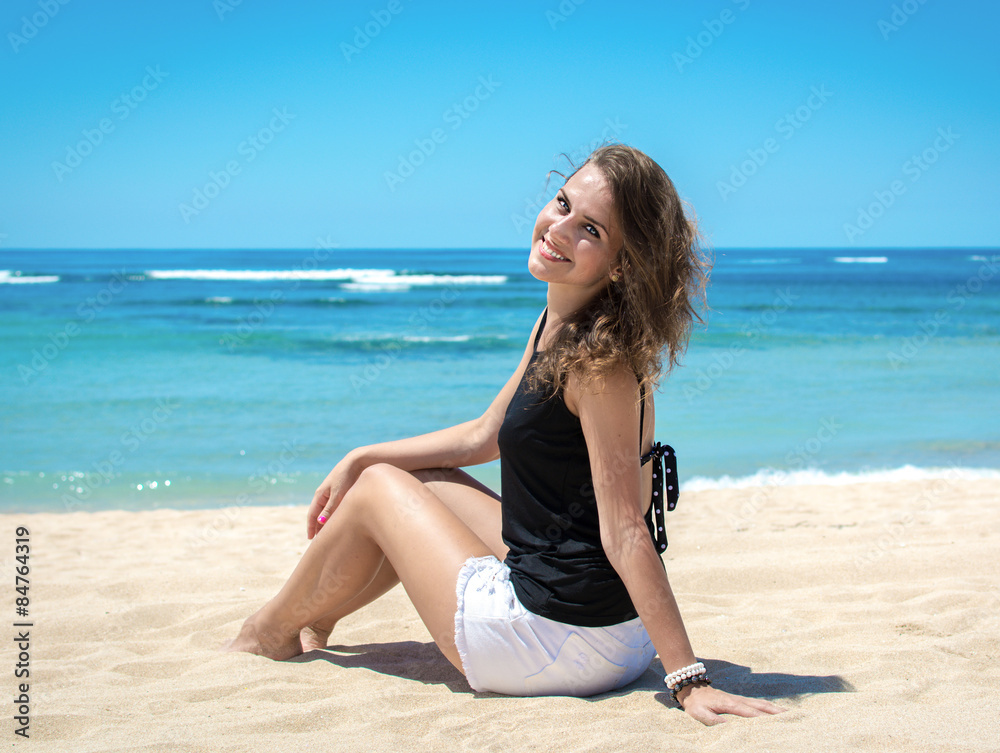 Young woman sitting on the beach and relaxing 