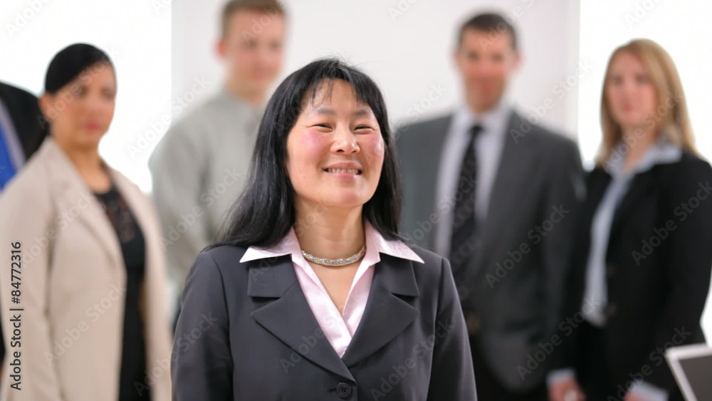 Portrait of Asian business woman with co-workers in background Portrait of Asian business woman with co-workers in background