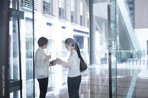 Two women have a chatting in the glass-walled building