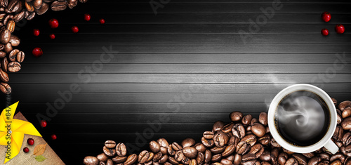Coffee cup and coffee beans on a black wooden table. Dark background © Tabthipwatthana