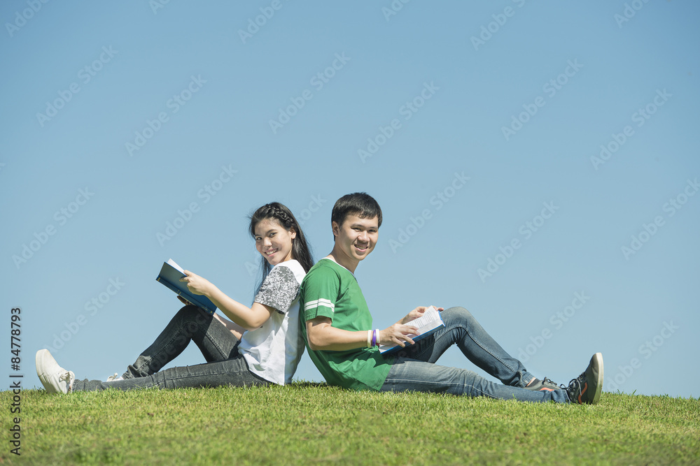 Young Asian couple sitting side by side and reading their books