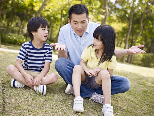 asian father and children talking in park