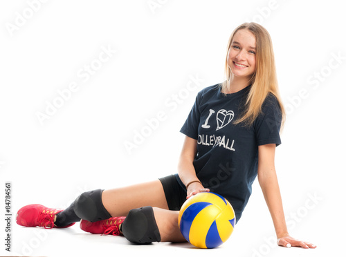 Volleyballspielerin sitzt lächelnd auf dem Boden 