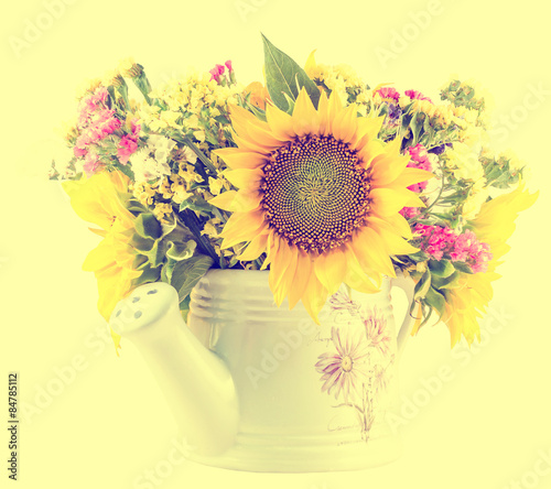 Yellow sunflowers and colored wild flowers in a white sprinkler