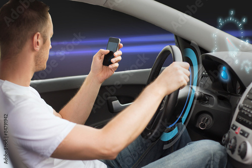 man looking to smart phone while driving car