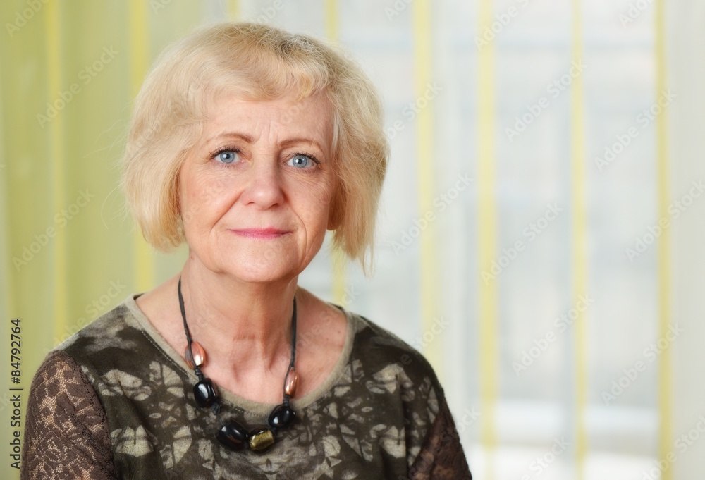 Mature blonde smiling woman in her room.
