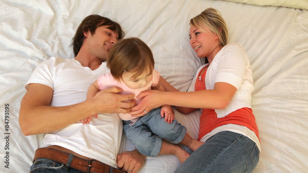 Family with young child playing together on bed Family with young child playing together on bed