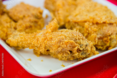 Crispy fried chicken on white plate closeup on red background