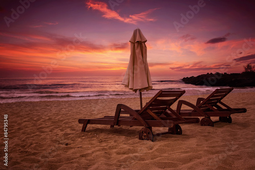 Sea sunrise view with two deck chairs and a beach umbrella