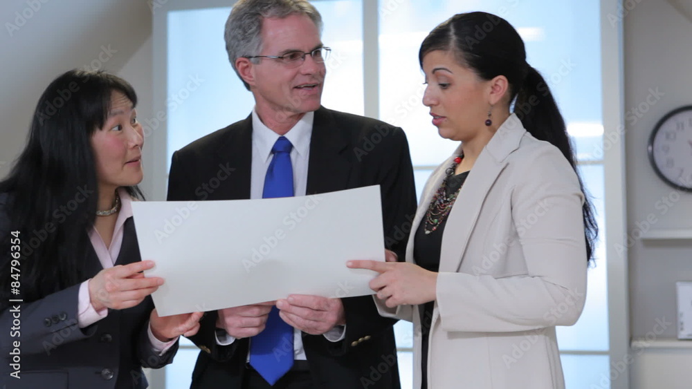 Group of businesspeople look at paper together Group of businesspeople look at paper together