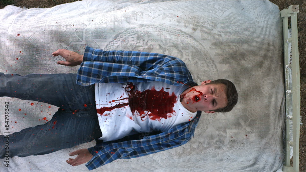 Overhead shot of man covered in blood falling, slow motion