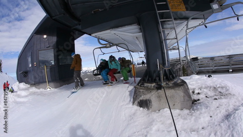 Four snowboarders unload from ski lift