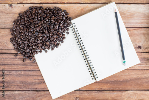 Pencil, notebook, coffee bean on wooden background