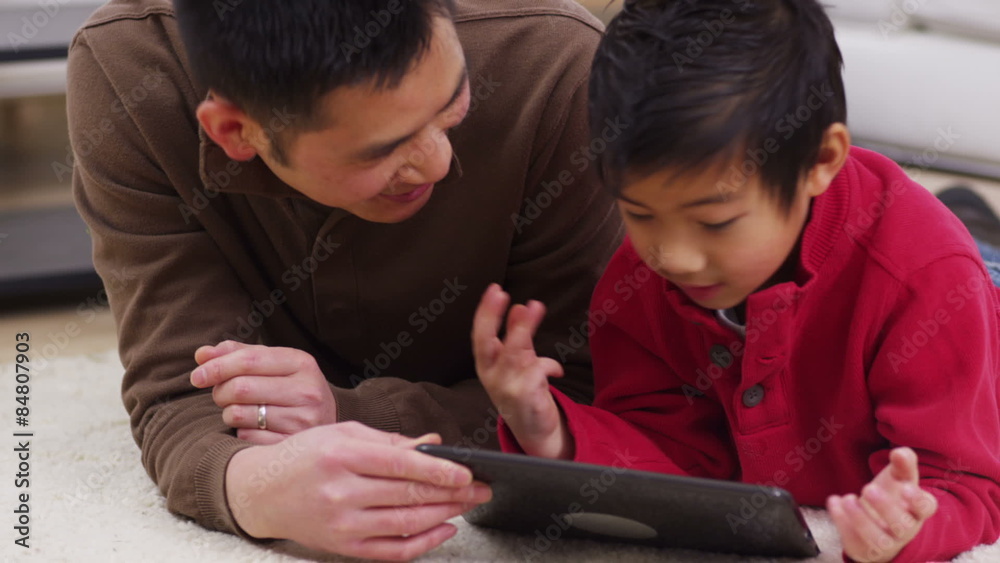 Father and son using a digital tablet together Father and son using a digital tablet together