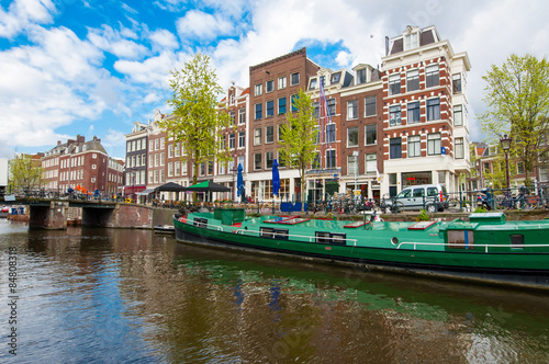 Amsterdam canal with a houseboat along the bank, Netherlands.