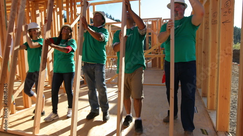 Volunteers working together lifting wall