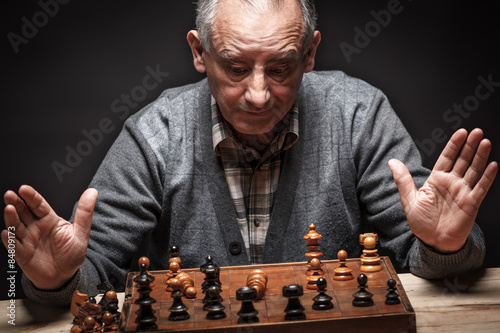 Senior man playing chess and thinking about next move