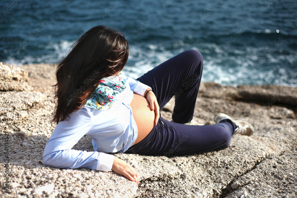 Schwangere Frau liegt am Meer
