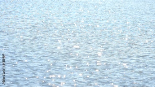 Light blue water surface glittering in the sun with sparkles