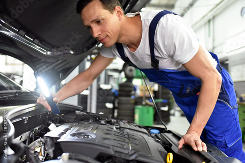 Automechaniker in Werkstatt repariert Fahrzeug